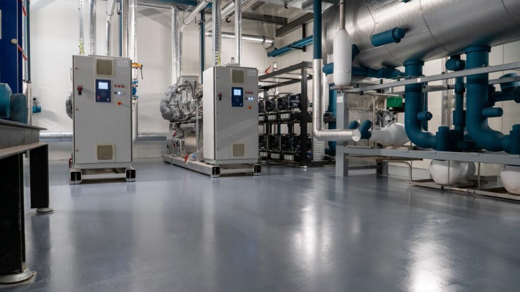 Industrial epoxy flooring installed in a commercial mechanical room with HVAC equipment.