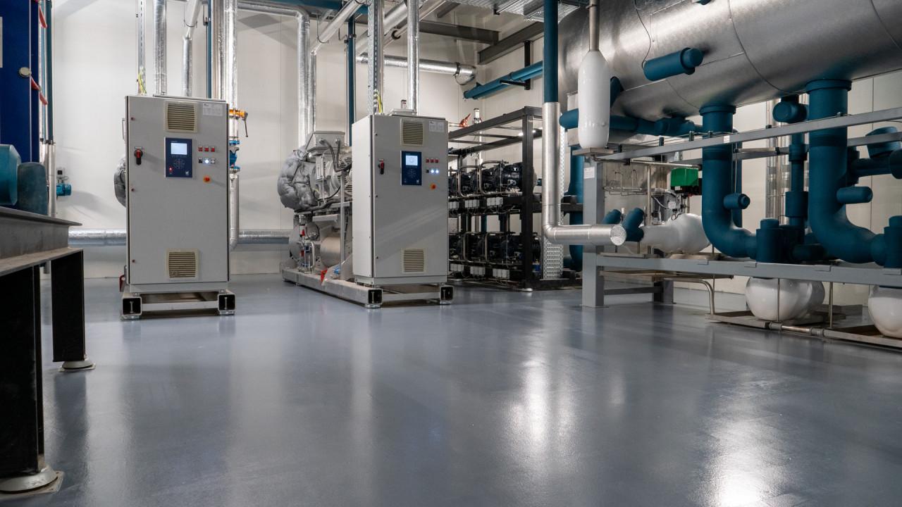 Industrial epoxy flooring installed in a commercial mechanical room with HVAC equipment.