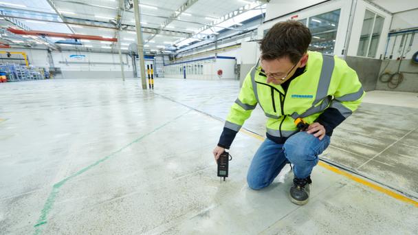 Engineer inspecting industrial flooring in a manufacturing facility